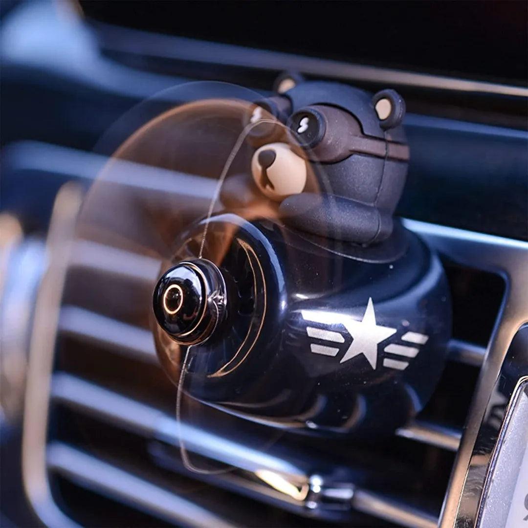 Bear pilot-themed car air freshener installed in a car, showing a close-up of the diffuser in action with the propeller spinning, providing a fresh and pleasant aroma.