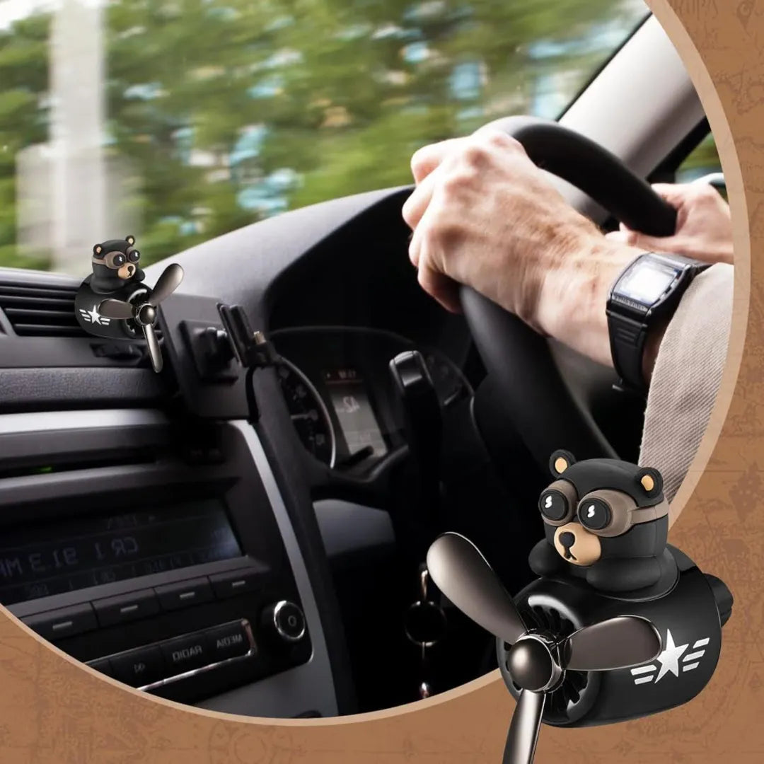 Bear pilot-themed car air freshener installed in a car, showing a driver holding the steering wheel, enhancing the car interior with a fun and functional decorative touch.