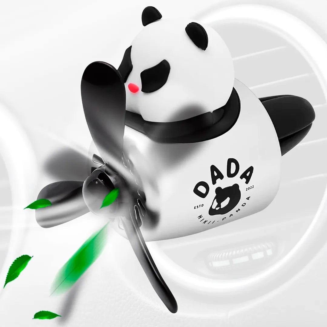 A panda-themed car air freshener with a black propeller, mounted on a car air vent. The panda figure sits on top of a silver and black airplane-shaped body with green leaves being blown by the propeller. The text on the body reads 'DADA' with a panda logo and 'ESTD 2022'. The background shows a white car interior.