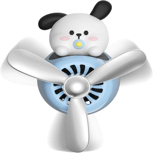 The image shows a car air freshener featuring a cute dog with a pacifier, sitting atop a blue propeller. The design is playful and childlike, with the dog having blush cheeks and black ears. The propeller is metallic and adds a whimsical touch to the air freshener, making it both functional and decorative.
