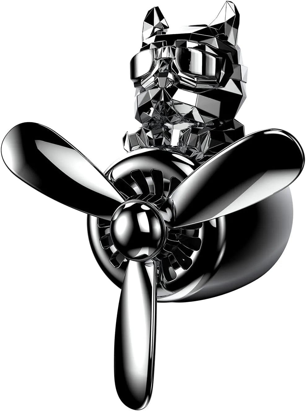 The image shows a close-up view of a bulldog pilot car air freshener with a propeller design. The bulldog figure has a sleek, faceted surface and is wearing aviator goggles. The air freshener has a metallic finish, and the propeller is prominently displayed at the front. The background is plain white, highlighting the detailed design of the air freshener.