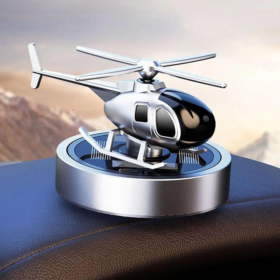Silver solar-powered helicopter propeller car air freshener displayed on a dashboard, providing a modern and elegant fragrance solution for vehicles.